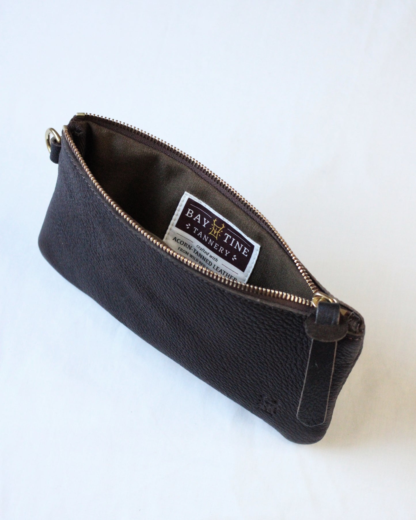 Brown leather zip pouch with "Dartmoor" embossed, made by Bay Tine Tannery, featuring a metal zipper and compact design.